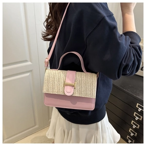 Dettaglio di una borsa a tracolla intrecciata rosa e beige indossata da una modella