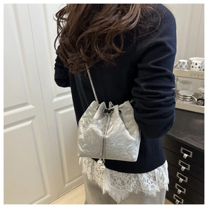 Detail of silver metallic bucket bag with pearl tassels and butterfly buckle ornament