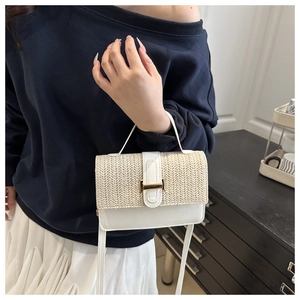 Close-up of contrast crossbody bag featuring straw flap and gold square metal lock