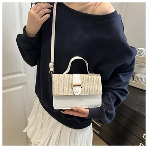 Detail of woven straw and white leather crossbody bag with gold buckle hardware