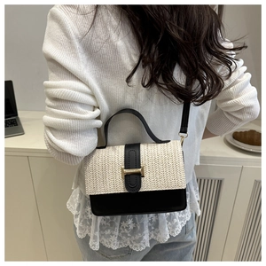 Detail of a color-block woven handbag on a model in a minimalist home setting