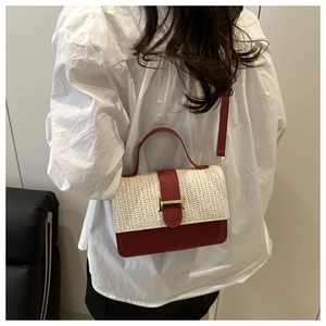 Close-up of woven straw and red leather shoulder bag with gold metal buckle