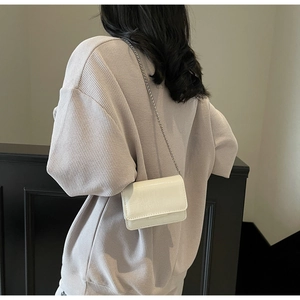 Close-up of white crocodile pattern leather crossbody bag with silver chain strap