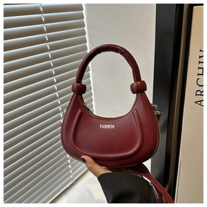 Detail of burgundy crescent handbag with knotted handle and white fashion text detail