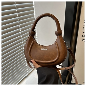 Detail of brown crescent bag showing matte leather texture and FASHION lettering