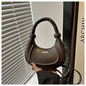 Detailed close-up of dark brown crescent bag with white Fashion logo and sturdy handle