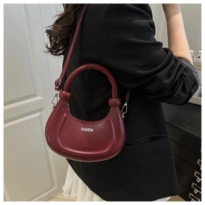 Detail of burgundy crescent bag with thick circular handle and fashion printing