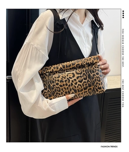 Detail of leopard print envelope clutch with metal ring closure held by a model