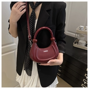 Detail view of burgundy moon bag with chunky handle and white fashion text logo