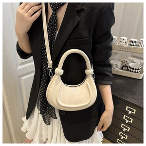 Detail of off-white crescent crossbody bag with minimalist FASHION text and leather strap