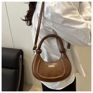 Detail of brown crescent bag with FASHION text and spherical handle ornament