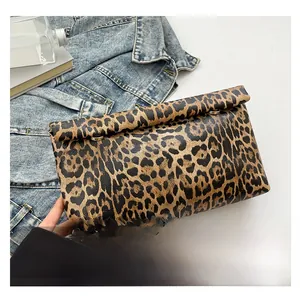 Detail of leopard print clutch with metal rings on denim background for fashion context