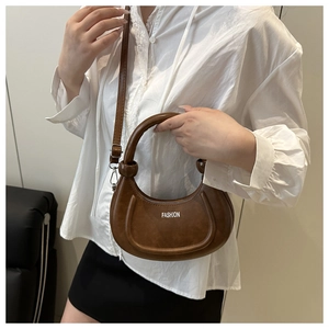 Macro shot of brown leather crescent bag with white Fashion print and pleated base details