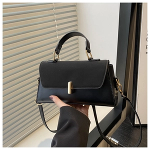 Close-up of matte black crossbody bag featuring a minimalist golden cylinder metal lock