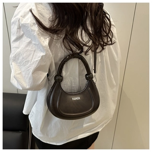 Detail view of the brown crescent moon handbag showing the leather texture and shoulder strap