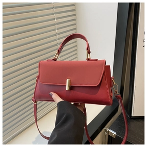 Detail of red leather square bag with elegant gold cylindrical lock and top handle