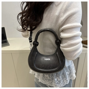 Detail of dark grey crescent shoulder bag with FASHION text and top handle for women