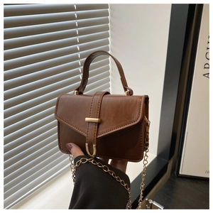 Detailed shot of brown PU leather handbag with gold metal chain and vintage handle