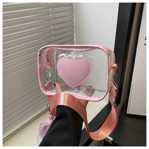 Dettaglio della toppa a cuore rosa sulla borsa a tracolla in PVC trasparente con tracolla