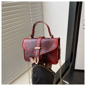 Detail of red snake-pattern handbag with gold rectangular buckle and metal chain strap