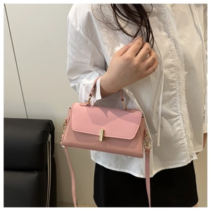 Detailed view of a pink crossbody bag with a gold rectangular buckle and long strap