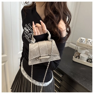 Detailed view of silver trapezoid handbag with metallic finish and delicate chain strap
