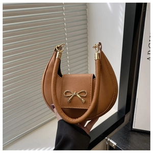 Detailed view of brown moon bag with gold bow clasp and cross-grain leather texture