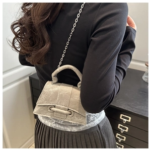 Detail of grey textured crossbody bag featuring metallic chain strap and round top handle
