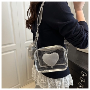Dettaglio decorazione a cuore argentato su borsa a tracolla trasparente con tracolla larga