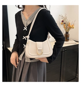 Dettaglio di una borsa hobo bianca minimalista con chiusura in metallo dorato a forma di U