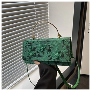 Close-up of lace embroidery and 3D butterfly detail on dark green crossbody bag