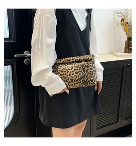 Dettaglio della pochette pieghevole con stampa leopardata tenuta da una modella in una stanza