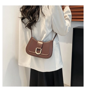 Elegante borsa sottobraccio in ecopelle marrone con fibbia dorata su modella in blazer.