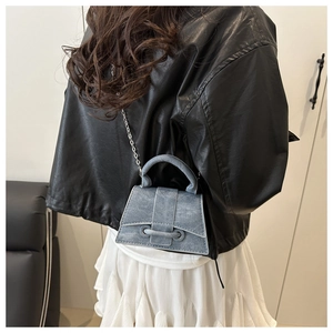 Detail of mini denim hourglass handbag with silver chain strap shown on a model