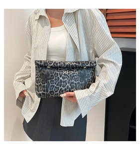 Detail of leopard print clutch bag shown with professional striped outfit in modern setting