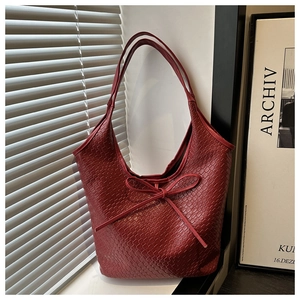 Detail of red woven tote bag with slim leather bow and dense texture craftsmanship