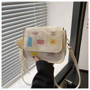 Close-up of cream crossbody bag with marble pattern, retro patches, and lace scarf charm