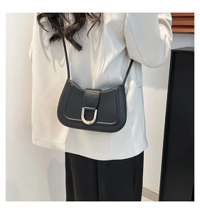 Close-up of black crossbody bag featuring a golden U-shaped buckle and fine matte leather