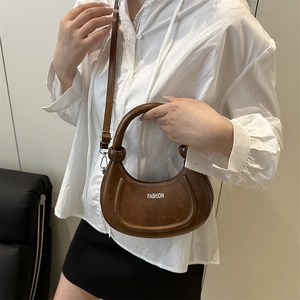 Brown half-moon crossbody bag with top handle and fashion print shown on model