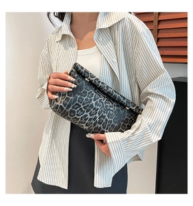 Detail of leopard print envelope clutch with gold metal buckle held by model