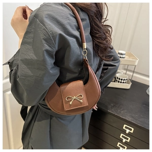 Detail view of brown dumpling bag with golden butterfly buckle and textured leather finish