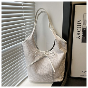 Detail of white woven textured tote bag with a decorative ribbon bow on the front