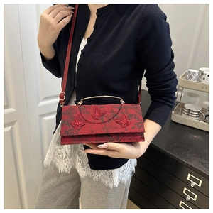 Detail of red crossbody bag with 3D butterfly embroidery and golden handle