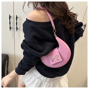 Detailed close-up of pink crescent underarm bag with gold bow buckle and leather texture