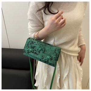 Close-up of green lace handbag with 3D butterfly embroidery and gold metal handles
