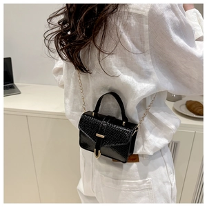 Detail of black faux leather mini square bag with snake skin texture and gold chain