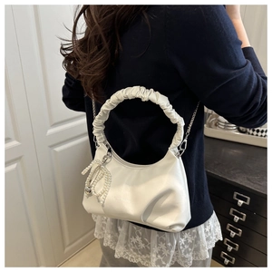 Close-up of white pleated cloud bag featuring pearl charm and silver chain strap