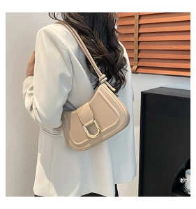 Elegante bolso de hombro en cuero beige con hebilla en D dorada llevado por modelo