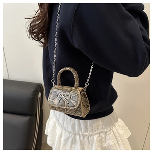 Nahaufnahme der Mini-Tasche mit Schlangenmuster, silberner Schleife und langer Metallkette