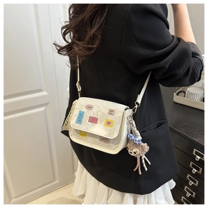 Detail of cream crossbody bag with cute prints and plush pendant on model back view
